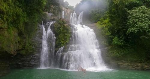 a waterfall in the jungle with people in the water at Paradiselodge Jungleguesthouse in Platanillo