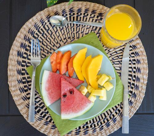 a plate of fruit on a table with a glass of orange juice at Paradiselodge Jungleguesthouse in Platanillo