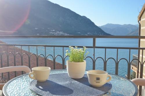 a table with two coffee cups and a vase on it at Apartment The Sea Coast in Kotor