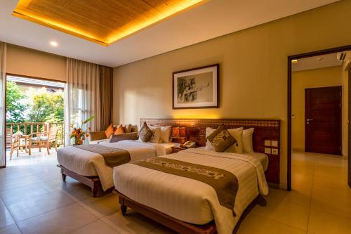 een hotelkamer met twee bedden en een balkon bij Radha Phala Resort & Spa in Ubud