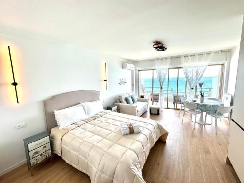 une chambre avec un grand lit et un salon dans l'établissement Casa Sud Menton Appartement rénové et moderne en front de mer à Menton, terrasse, cuisine équipée, climatisé, WiFi et Netflix, à Menton