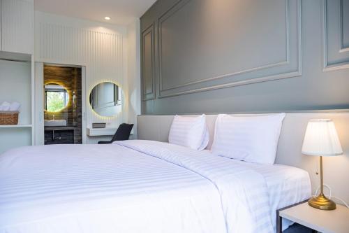 a bedroom with a large white bed with a lamp at Wellington Hotel Prachuapkhirikhan in Ban Nong Bua