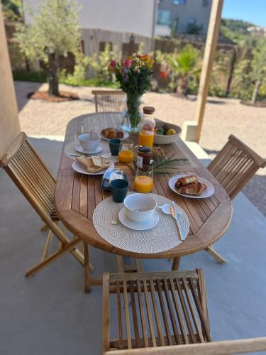 une table en bois avec des assiettes de nourriture et de jus d'orange dans l'établissement Appartement vue mer Volpaghja 02, à Cargèse