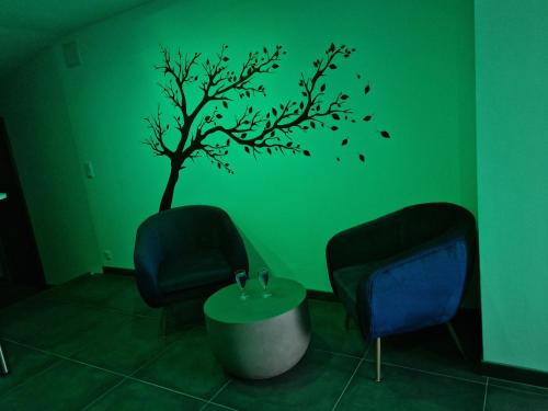 a green room with a tree and two chairs and a table at Nuit Blanche Normandie in Eu
