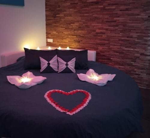 a black bed with a heart and two pink flowers at Nuit Blanche Normandie in Eu