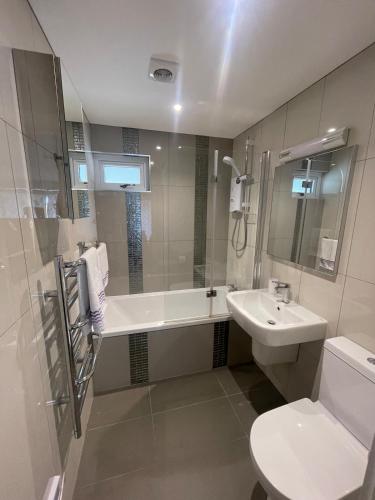 a bathroom with a sink and a tub and a toilet at TWIN COVES at Curlew 1, The Cove, Brixham in Brixham