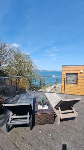 a patio with two chairs and a picnic table and the ocean at TWIN COVES at Curlew 1, The Cove, Brixham in Brixham