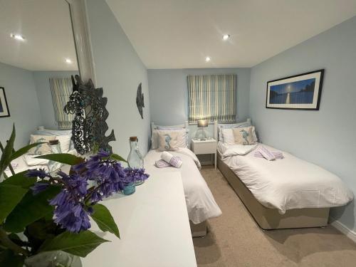 a room with two beds and a table with purple flowers at TWIN COVES at Curlew 1, The Cove, Brixham in Brixham