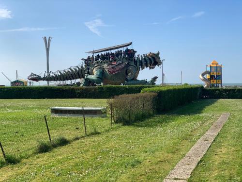 une grande statue de dinosaure assise au sommet d'un champ dans l'établissement Front de Mer, à Calais