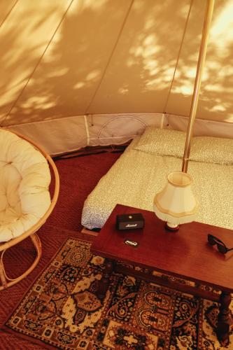 une table avec une lampe et un lit dans une tente dans l'établissement Tente Double - Hegoa Surf Camp Pays Basque, à Saint-Jean-de-Luz