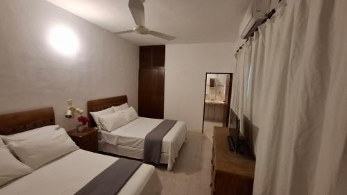 a hotel room with two beds and a ceiling fan at Casa del Viento Celestun in Celestún