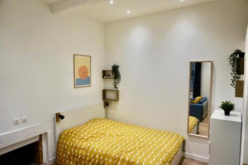 - une chambre avec un lit jaune et un miroir dans l'établissement Studio calme et tout équipé centre historique, à Aix-en-Provence