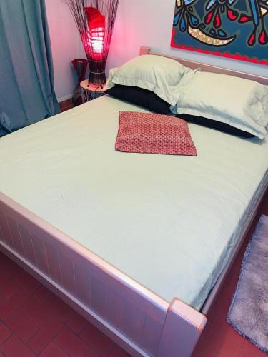 un lit avec un matelas blanc et un oreiller rouge dans l'établissement Soleil couchant aux reflets miel de la terre, à Canet