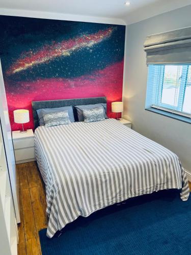 a bedroom with a bed with a painting on the wall at Ely Cathedral family home in Ely