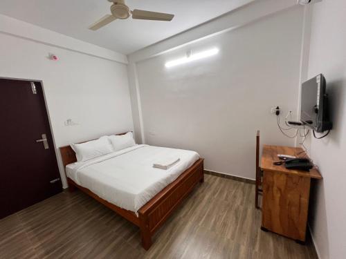 a small bedroom with a bed and a television at Ashtapadi Inn in Guruvāyūr