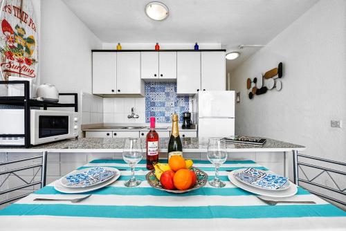 a kitchen with a table with a bowl of fruit and wine bottles at Holiday Dream near Yumbo in Playa del Ingles