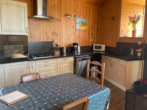 une cuisine avec une table et une cuisinière four supérieur dans l'établissement Gîte Le chant des mésanges avec 3 chambres, à Tence