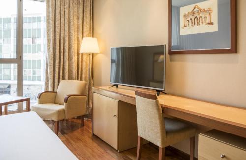 a hotel room with a desk with a flat screen tv at Ilunion Alcalá Norte in Madrid