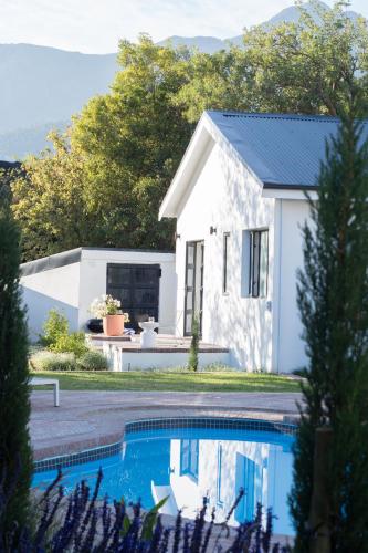a white house with a swimming pool in front of it at Maison la Bruyere, 8p villa - heated pool, airco & hottub in Franschhoek