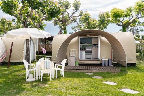 a tent with a table and chairs in a yard at Camping Fossalta in Lazise