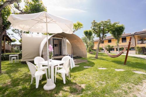 a table and chairs under an umbrella in a yard at Camping Fossalta in Lazise