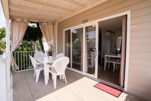 a patio with white chairs and a table on a porch at Camping Fossalta in Lazise