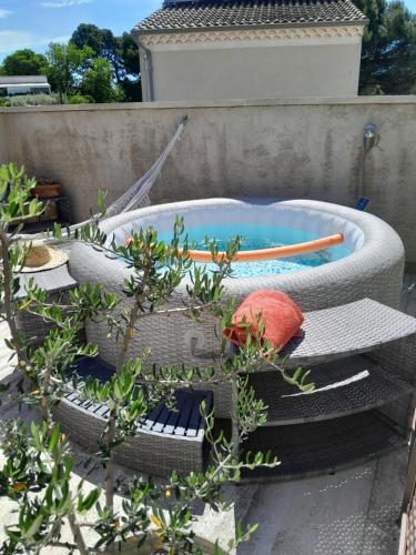 une piscine avec une chaise en osier et des plantes dans l'établissement Le Mazet de l'Acacia, à Beaumes-de-Venise