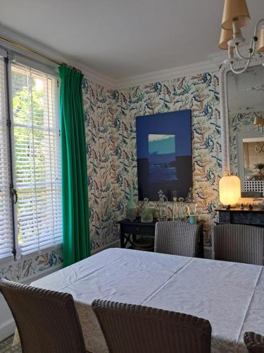 une salle à manger avec une table et des rideaux verts dans l'établissement Le Clos Chaillan, à Cinq-Mars-la-Pile