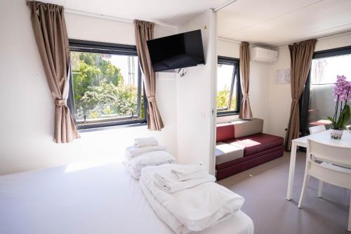 a hotel room with three beds and a television at Camping Fossalta in Lazise