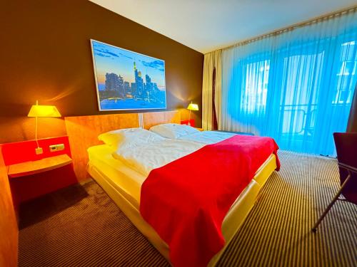 a hotel room with a bed with a red blanket at Hotelzimmer mit einer Kitchenette - nähe Frankfurt-Messe - fair in Frankfurt/Main