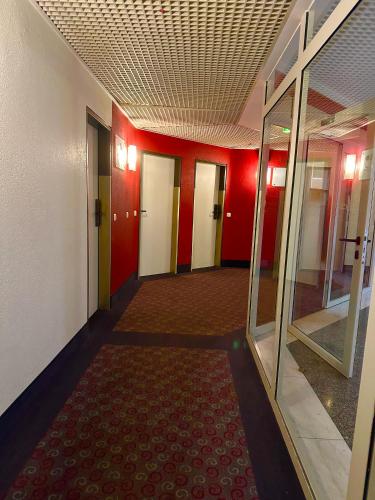 an empty hallway with red walls and a red carpet at Hotelzimmer mit einer Kitchenette - nähe Frankfurt-Messe - fair in Frankfurt/Main