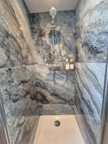 La salle de bains est pourvue d'une douche et d'un mur en pierre. dans l'établissement Escale 4 étoiles à Notre Dame de Monts, vue mer, à Notre-Dame-de-Monts