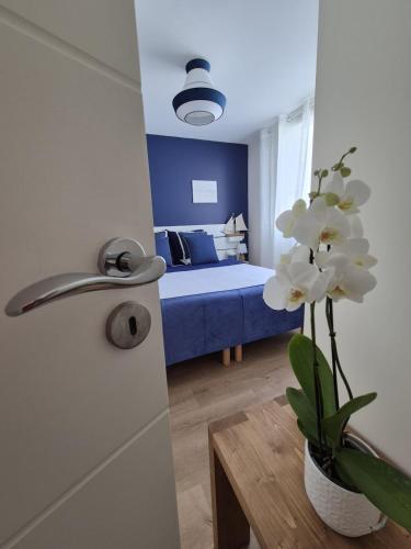 Cette chambre comprend un lit et un vase avec des fleurs blanches. dans l'établissement Escale 4 étoiles à Notre Dame de Monts, vue mer, à Notre-Dame-de-Monts