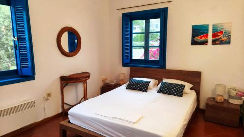 una camera da letto con un letto bianco e finestre blu di Stamos house a Hydra