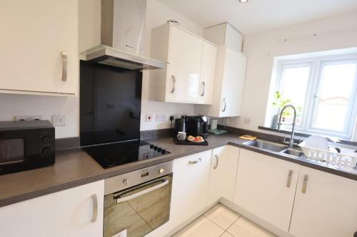 une cuisine avec des armoires blanches et un appareil noir dans l'établissement 3 BR - 3 Baths - Solihull - NEC - HS2 - Long Stays, à Olton