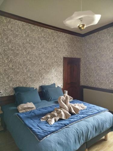 une chambre avec un lit bleu avec des serviettes dessus dans l'établissement Aux Tilleuls de Renaison, à Renaison