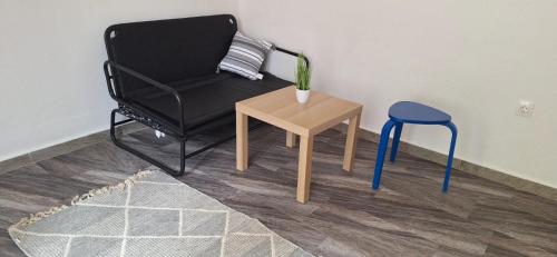 a black chair and a blue stool next to a table at Michaniona apartment in Néa Michanióna