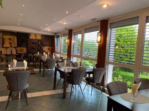 a restaurant with tables and chairs and windows at Katalin Motel & Étterem in Berettyóújfalu