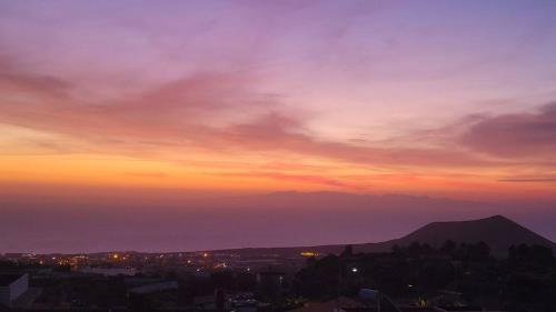 a sunset over a city with a mountain in the background at Finca Maradentro - private pool and jacuzzi with ocean view in Arafo