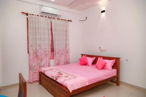 Un dormitorio con una cama con almohadas rosas y una ventana. en Villa Kaluperuma, en Beruwala