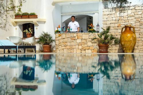 a man sitting at a bar next to a swimming pool at Villa La Meridiana - Caroli Hotels in Leuca