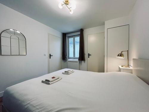 une chambre blanche avec un grand lit blanc et une fenêtre dans l'établissement 4 clairmarais T2 chic et cocooning proche centre, à Reims