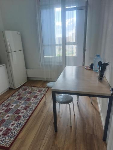 a kitchen with a table and a chair and a refrigerator at Satsiti Блок Н in Astana