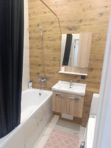 a bathroom with a tub and a sink and a mirror at Satsiti Блок Н in Astana