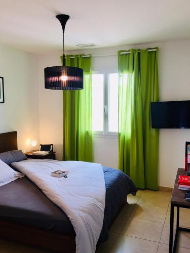 - une chambre avec des rideaux verts et un lit dans l'établissement Maison proche de Perpignan et de la mer, à Pia