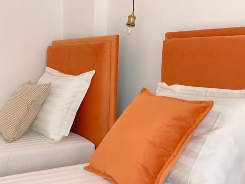 two beds with orange and white pillows in a room at PROMO Elegant Apartments NEW - Colorful by the sea in Durrës