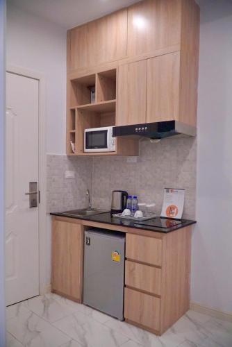 a small kitchen with wooden cabinets and a microwave at D Eco Wellness Center in North Pattaya