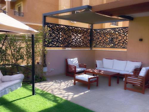 a patio with a table and chairs and an umbrella at شقة فاخرة 3 غرف نوم و حديقة خاصة في الشيخ زايد - Zayed Suites A in Sheikh Zayed