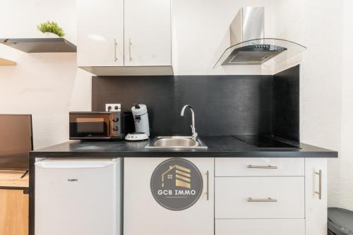 une cuisine avec un évier et un micro-ondes dans l'établissement Le Petit Saint Paul, à Grenoble