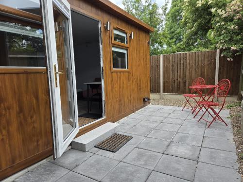 a patio with a red chair and a sliding glass door at Secret Garden Studio in Eltham